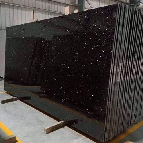 Polished black granite slabs with gold flecks, stacked in our yard
