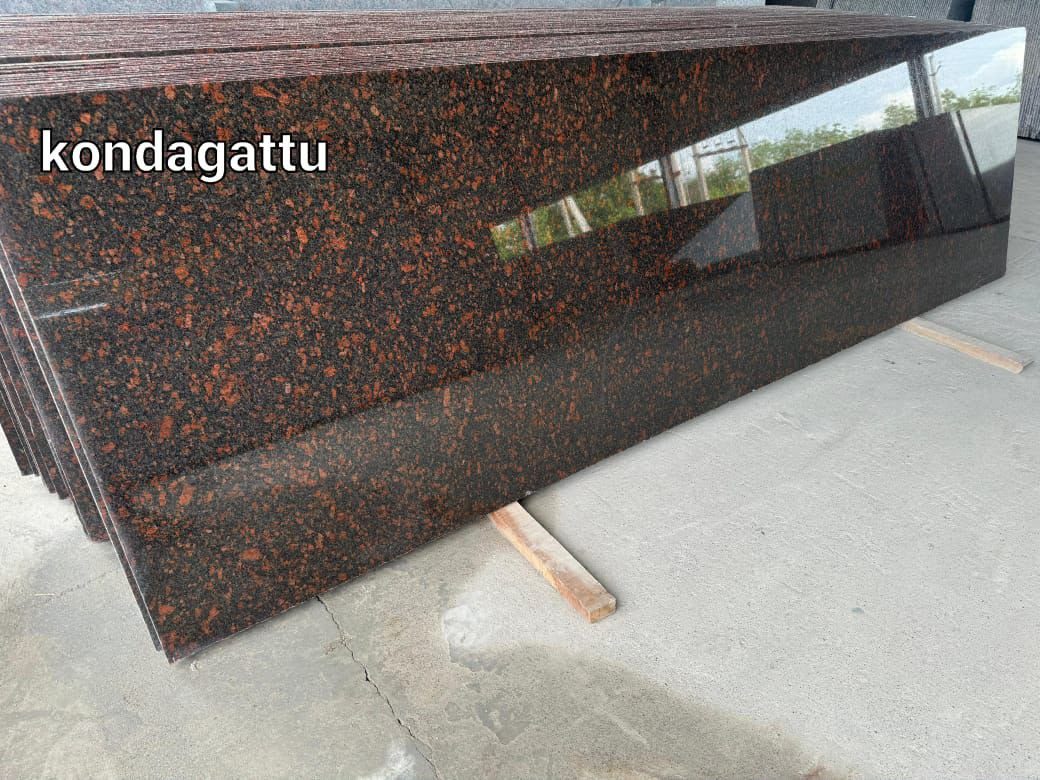 Stack of polished red-brown flecked granite slabs labelled kondagattu