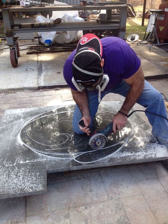 Craftsman hand-finishing a carved stone basin with a grinder