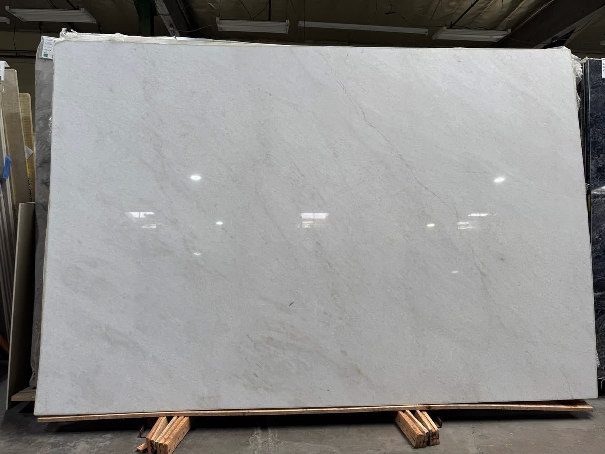 Large polished white slab with soft grey veining on a slab rack