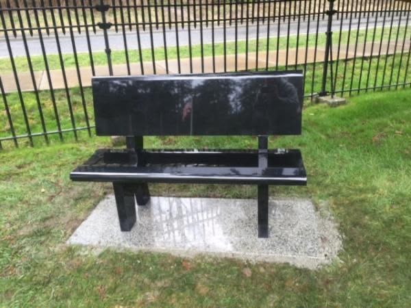Black granite garden bench on a lawn