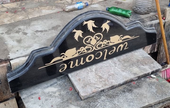 Arched black granite sign with gold engraved Welcome lettering and bird motifs