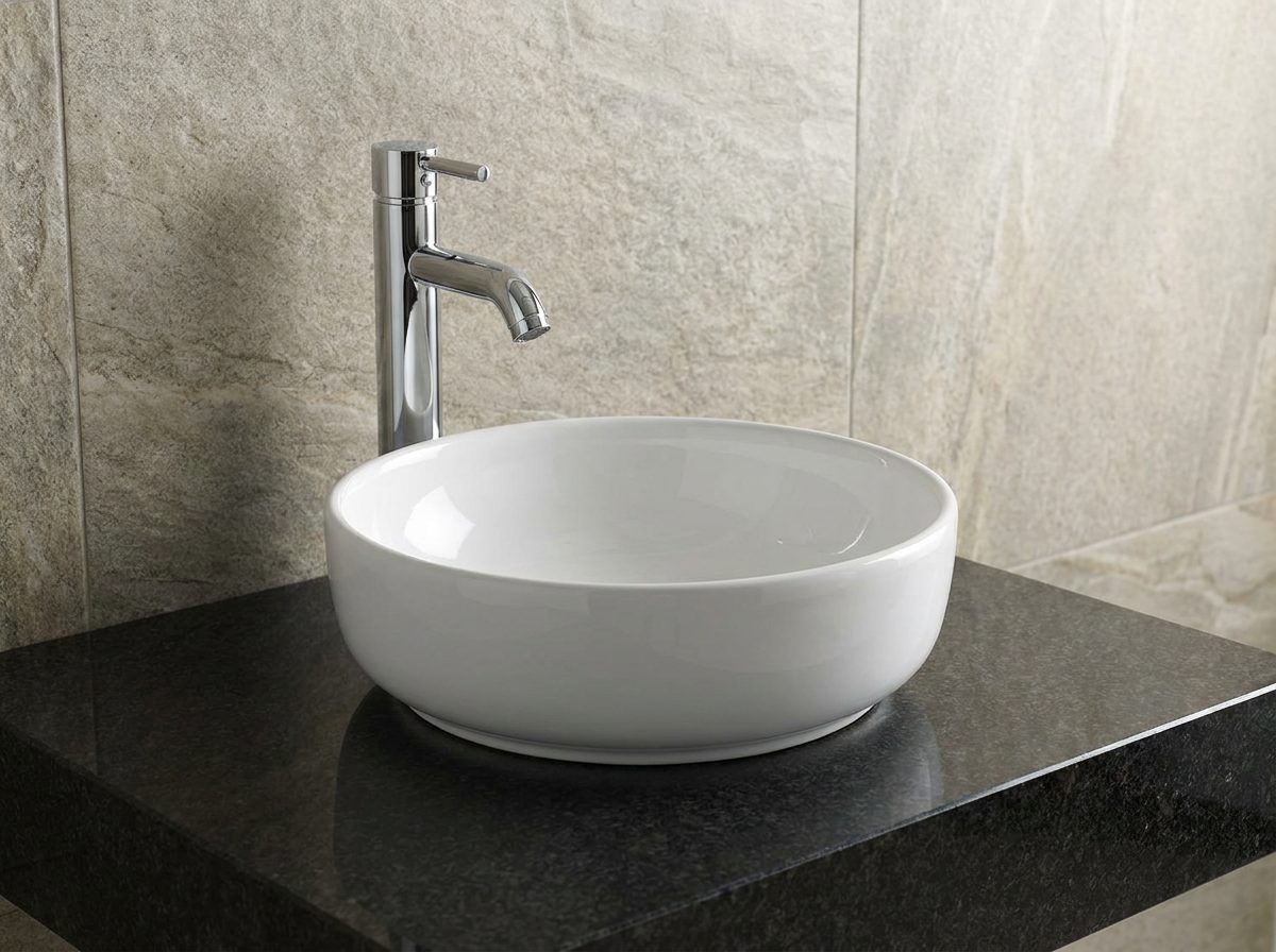 Round white ceramic countertop basin on a dark granite vanity